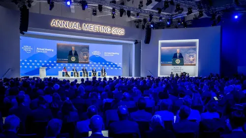 ترامب يتحدث أمام المنتدى الاقتصادي العالمي في دافوس 2025، مع حشد كبير في الخلفية ولافتات توضح الحدث.