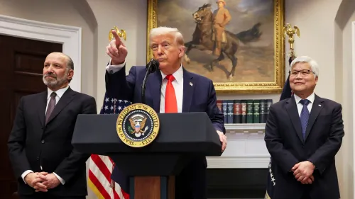 ترامب يتحدث خلال مؤتمر صحفي في البيت الأبيض، مع وجود علم أمريكي خلفه، بينما يستمع له مساعدوه.