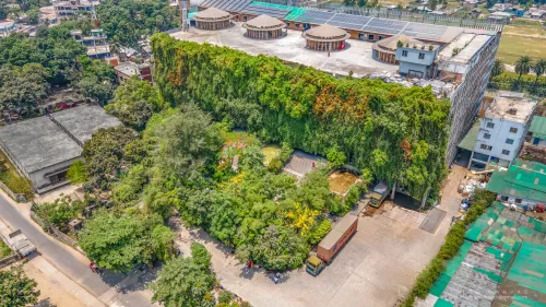 مصنع Green Field في بنغلاديش مغطى بجدار نباتي وحدائق داخلية، يعكس تصميمًا مستدامًا يدمج الطبيعة لتحسين بيئة العمل.