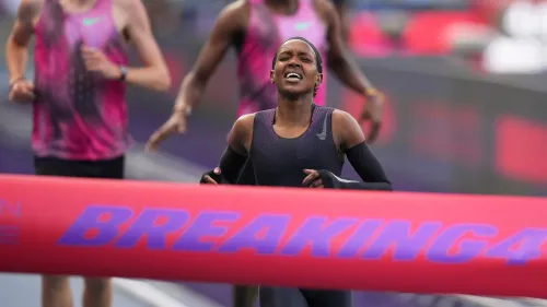 كيبيغون تعبر خط النهاية في سباق Breaking4، تعبير عن الجهد والتحدي، محاطة بأجواء تشجيعية من الجماهير.