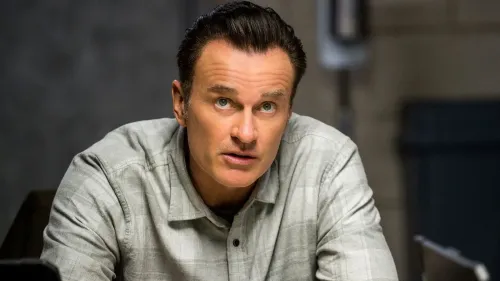 جوليان ماكماهون في مشهد من مسلسل "FBI: Most Wanted"، حيث يعكس تعابير الجدية والاهتمام في دوره.
