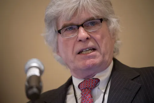 تظهر الصورة بيتر بريميلو، الناشط اليميني المتطرف، خلال حديثه في مؤتمر. يركز المقال على اتهامات إساءة استخدام أصول مؤسسة VDARE.