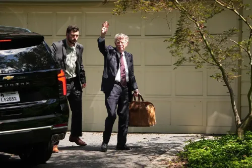 جون بولتون يغادر منزله في بيثيسدا بولاية ماريلاند، حاملاً حقيبة، بينما يلوح بيده، وسط تحقيقات فدرالية حول الوثائق السرية.