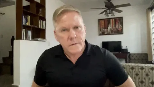 رجل يجلس في غرفة معيشة، يبدو عليه التركيز والجدية، مع خلفية تحتوي على أرفف كتب وأثاث مريح، في سياق نقاش حول قضايا قانونية وسياسية.