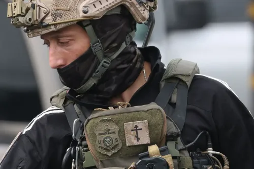 ضابط إنفاذ قانون يرتدي ملابس تكتيكية وقناعًا، مع شارة على صدره، في سياق العمليات الأمنية في كاليفورنيا.