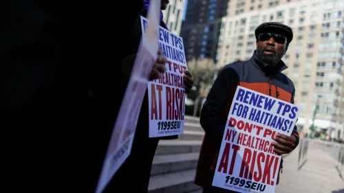 رجل يحمل لافتة تطالب بتجديد وضع الحماية المؤقتة للهايتيين، يظهر في تظاهرة للدفاع عن حقوق المهاجرين في نيويورك.