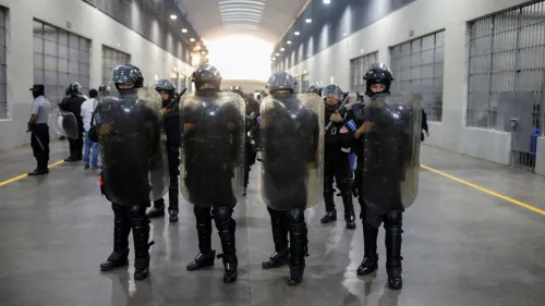 قوات أمنية ترتدي دروعًا واقية في ممر سجن كبير بالسلفادور، خلال جلسة استماع قانونية حول ترحيل المهاجرين.