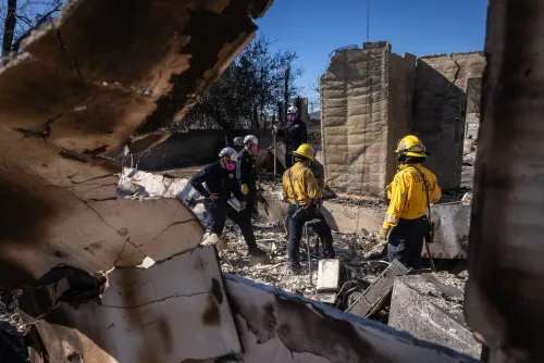 فرق الإنقاذ تعمل في موقع حريق مدمر، حيث تظهر آثار الدمار في المنازل المحترقة، مما يبرز الحاجة إلى تمويل التأهب للكوارث.