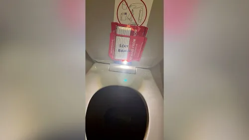 ملصقات حمراء على مقعد مرحاض الطائرة، تحمل تحذيرات عن عدم صلاحية الاستخدام، مع وجود هاتف مخفي لتسجيل الفيديو.