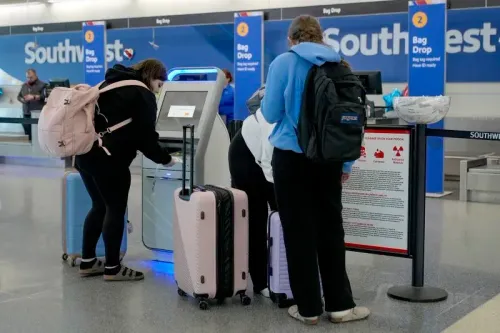 مسافرون يقفون أمام كشك تسجيل الوصول في مطار تابع لشركة ساوث ويست، يحملون حقائبهم ويتابعون التعليمات.