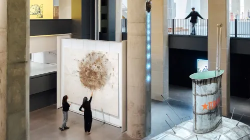 داخل متحف كارتييه للفنون، زوار يتفاعلون مع عمل فني كبير، بينما تُظهر المساحة المعمارية الحديثة تفاصيل التصميم الفريد والإضاءة الطبيعية.