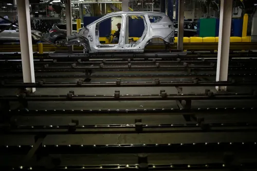 هيكل سيارة كهربائية في مصنع فورد، مع خطوط تجميع جديدة في الخلفية، تعكس تحول الشركة نحو الإنتاج الكهربائي.