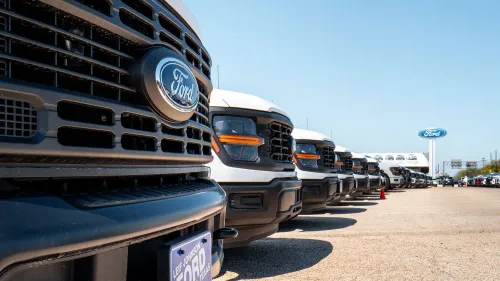 صف من شاحنات فورد الجديدة في ساحة عرض، مع التركيز على شعار فورد، في سياق زيادة مبيعات السيارات في مارس.