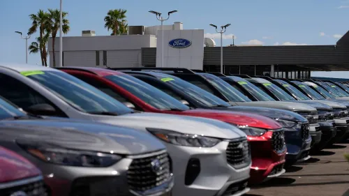 صف من السيارات الجديدة المتاحة للبيع في معرض فورد، مع وجود لافتات أسعار عليها، وخلفية المبنى المخصص لشركة فورد.