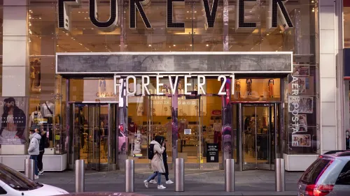 واجهة متجر Forever 21 في مدينة مزدحمة، مع زبائن يتجولون أمامه، تعكس التحديات التي تواجه العلامة التجارية في سوق الأزياء السريعة.