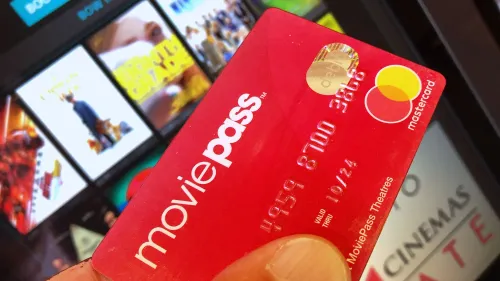 بطاقة MoviePass حمراء، تُظهر شعار الخدمة، مع خلفية تضم إعلانات أفلام، تعكس الجدل حول الاحتيال في الأوراق المالية.