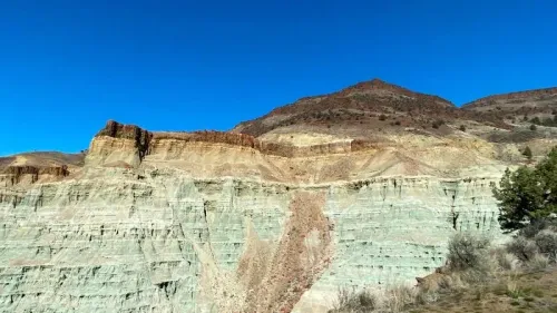 منظر طبيعي لجبال وأراضي شاسعة في ولاية أوريغون، مع تدرجات لونية متنوعة في الصخور، يبرز أهمية الاكتشافات الأحفورية في المنطقة.