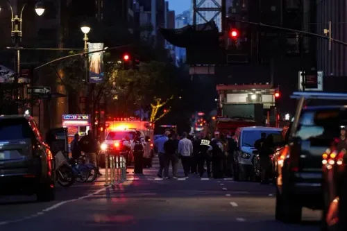موقع الحادث في مانهاتن بعد إطلاق نار، يظهر سيارات الشرطة والإسعاف، مع تجمع الناس في الشارع وسط أجواء مشحونة.