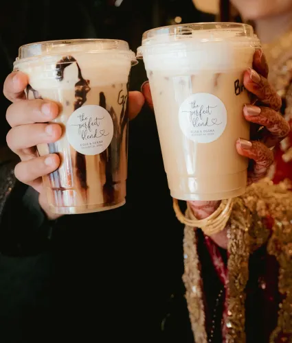أكواب مشروبات مميزة تحمل علامة "المزج المثالي"، ممسكة بأيدٍ مزينة بالحناء، تعكس أجواء حفلات الزفاف في جنوب كاليفورنيا.