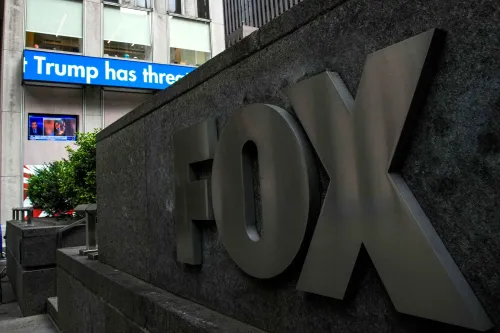 شعار قناة فوكس نيوز يظهر في المقدمة، مع شاشة تعرض أخبار تتعلق بالرئيس ترامب. تعكس الصورة التوترات حول حرية الصحافة والتعديل الأول.