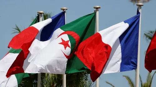 أعلام الجزائر وفرنسا وإيطاليا ترفرف معًا، تعكس تصاعد التوترات الدبلوماسية بين الجزائر وفرنسا عقب طرد المسؤولين.