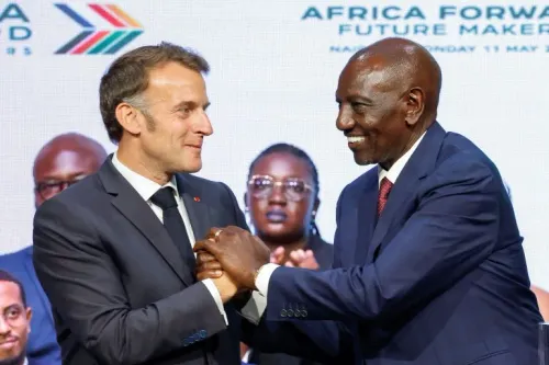 الرئيس الفرنسي إيمانويل ماكرون ورئيس كينيا ويليام روتو يتصافحان خلال قمة "Africa Forward" في نيروبي، مع خلفية تضم قادة أفارقة.
