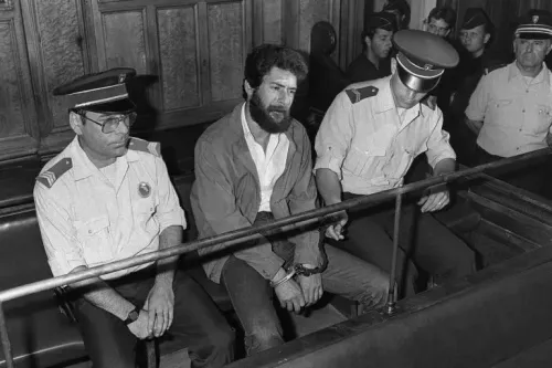 جورج إبراهيم عبد الله، المناضل اللبناني، يجلس في قاعة المحكمة محاطًا برجال الشرطة، خلال محاكمته في الثمانينيات.