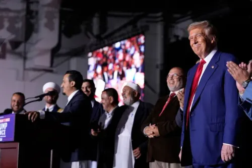 دونالد ترامب يقف مبتسمًا في تجمع انتخابي بديربورن بميشيغان مع أئمة ومسلمين محليين، في سياق دعم المجتمع العربي الأمريكي لانتخابات 2024.