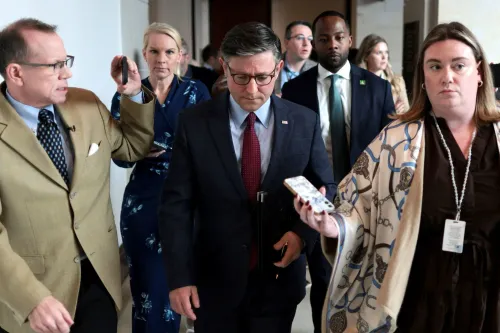 مجموعة من الأشخاص في مبنى حكومي، يتحدثون مع بعضهم البعض بينما يبدو أحدهم مشغولًا بالهاتف، مما يعكس أجواء العمل السياسي.