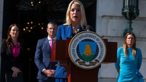 تظهر الصورة بام بوندي، المدعي العام، تتحدث أمام منصة تحمل شعار وزارة الزراعة، مع عدد من المساعدين خلفها.