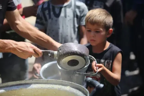 طفل صغير يحمل وعاءً أثناء توزيع الطعام في غزة، وسط مجموعة من الأطفال، في ظل الظروف الإنسانية الصعبة الناتجة عن الحرب.