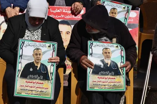 أشخاص يحملون صور الطبيب الفلسطيني حسام أبو صفية المحتجز في إسرائيل، مطالبين بالإفراج عنه وإنقاذ حياته وسط تدهور الوضع الصحي في غزة.