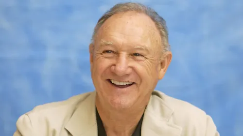 تعبير عن جين هاكمان مبتسم، مع خلفية زرقاء. يُعتبر هاكمان ممثلاً بارزًا، معروفًا بأدواره القوية في السينما الأمريكية.