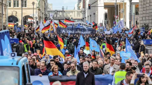 تجمع حشود كبيرة في شارع رئيسي في ألمانيا، حاملة لافتات وأعلام، تعبر عن دعمها لحزب البديل من أجل ألمانيا وسط جدل سياسي حول تصنيفه ككيان متطرف.