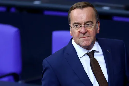 وزير الدفاع الألماني كارستن بروير خلال مؤتمر، مع خلفية مقاعد باللون الأرجواني، يعبر عن التزام ألمانيا بتعزيز قواتها المسلحة.