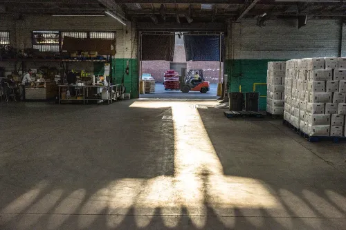 مستودع فارغ مع شاحنة نقل في الخلفية، يبرز الضوء من المدخل. الصورة تعكس تأثيرات البيانات الاقتصادية على سوق العمل.