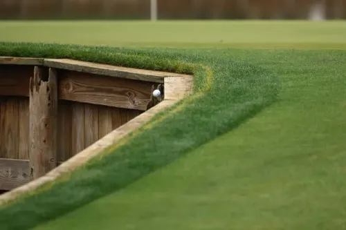 كرة غولف على حافة خشبية محاطة بالمياه في الحفرة رقم 17 في TPC Sawgrass، تعكس لحظة توتر خلال بطولة اللاعبين.