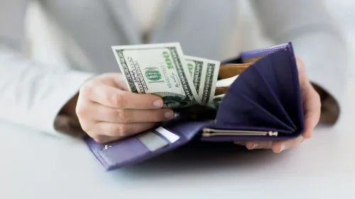 يد تحمل نقودًا داخل محفظة، مع التركيز على أهمية استخدام الأموال المستردة لتحسين الوضع المالي، مثل سداد الديون أو الادخار.