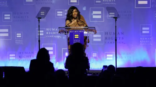 النائبة جاسمين كروكيت تتحدث في حدث لحملة حقوق الإنسان، مع خلفية تحمل شعار الحملة، وسط تفاعل الجمهور.