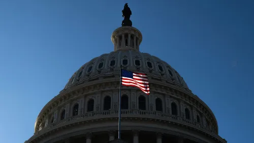 قبة مبنى الكابيتول الأمريكي تضيء تحت السماء الزرقاء، مع العلم الأمريكي يرفرف بفخر، في سياق مناقشات حول إصلاح برنامج Medicaid.