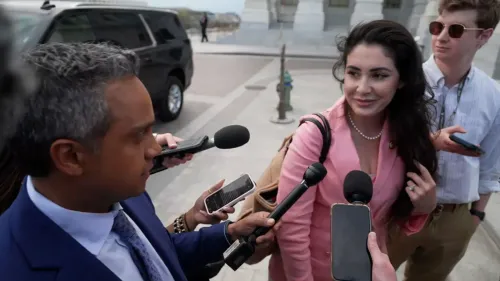 النائبة آنا باولينا لونا تتحدث مع الصحفيين خارج مبنى الكونغرس، محاطة بمجموعة من الميكروفونات، تعبر عن مواقفها حول التصويت بالوكالة للآباء الجدد.