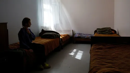 طفلة تجلس على سرير في غرفة فارغة، تعكس الأجواء الحزينة والمعاناة الناتجة عن النزاع في أوكرانيا.