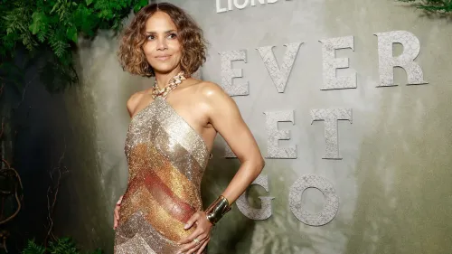 هالي بيري ترتدي فستانًا لامعًا خلال حدث، مع خلفية تحمل عبارة "Never Let Go"، تعبيرًا عن إنجازاتها كأول امرأة سوداء تفوز بجائزة الأوسكار.