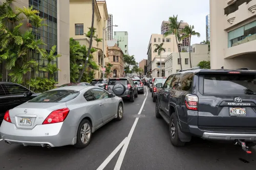 ازدحام مروري في وايكيكي، هاواي، مع سيارات متوقفة على جانب الطريق وأشجار النخيل المحيطة، مما يعكس حالة الطوارئ بعد إنذار التسونامي.