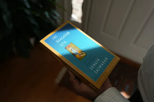 كتاب "البهاجavad غيتا" بترجمة إكناث إيسواران، ممسك به شخص، مع خلفية نباتية، يرمز إلى البحث عن الحكمة في الأوقات الصعبة.