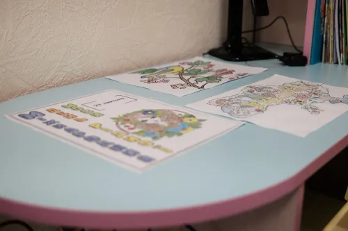 رسومات ملونة لأطفال على طاولة زرقاء، تتضمن مشاهد طبيعية وحيوانات، تعكس تأثير الحرب على الأوكرانيين واحتياجاتهم النفسية.