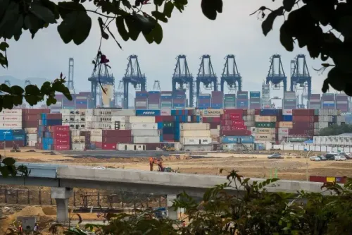 صورة لميناء يحتوي على حاويات شحن ملونة وأجهزة تحميل، تعكس تأثير التعريفات الجمركية على التجارة العالمية.