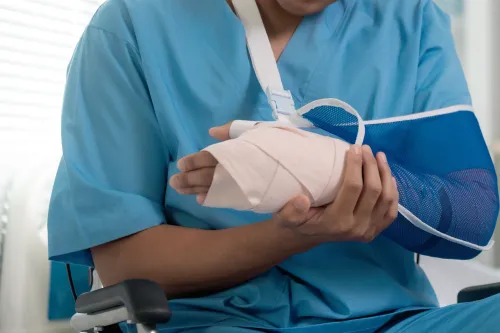 رجل يرتدي زيًا طبيًا يحمل ذراعه المصابة بجبيرة، مما يعكس التحديات المتزايدة في تكاليف الرعاية الصحية في الولايات المتحدة.