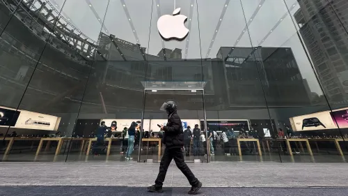 واجهة متجر آبل مع شعار الشركة، حيث يظهر زبائن يتصفحون المنتجات داخل المتجر، وسط توقعات بارتفاع أسعار الآيفون بسبب التعريفات الجمركية.