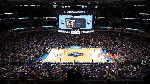 مدرج مزدحم خلال بطولة NCAA لكرة السلة، مع عرض لنتائج المباريات على الشاشة الكبيرة، مما يبرز أجواء جنون مارس.